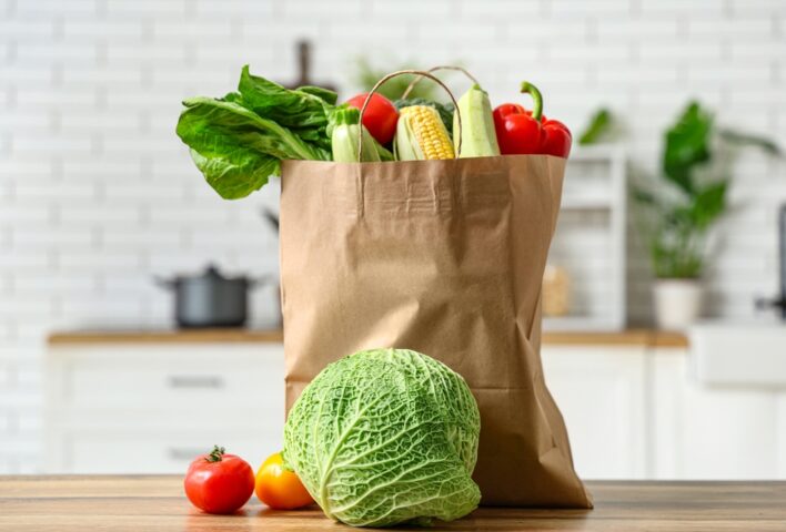 A paper grocery bag filled with fresh vegetables on a kitchen counter